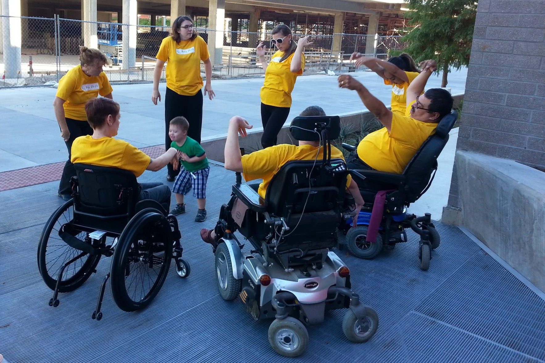 Six performers with and without disabilities form a circle and dance. A little boy dances in the center.