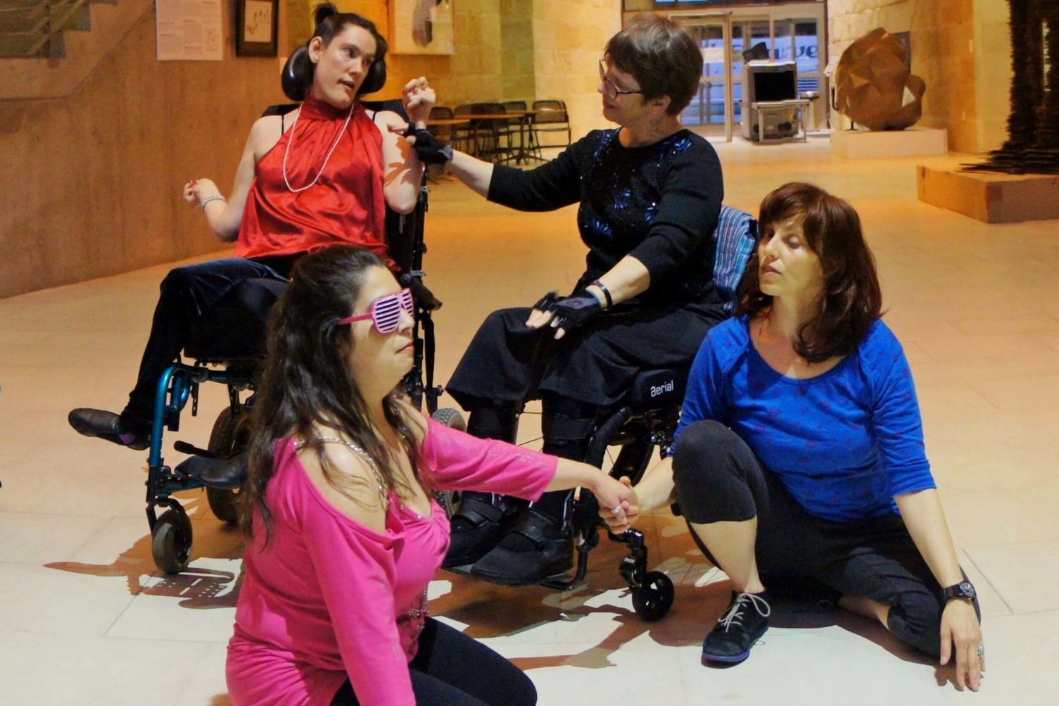 A group of 6 dancers with and without disabilities performing in an office hallway.