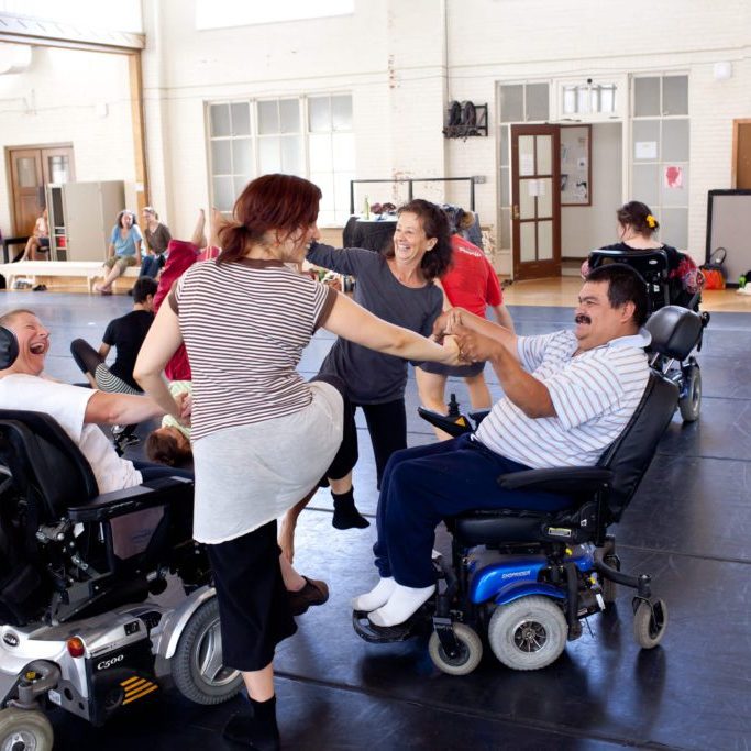 four dancers with and without disabilities standing in a circle and holding hands
